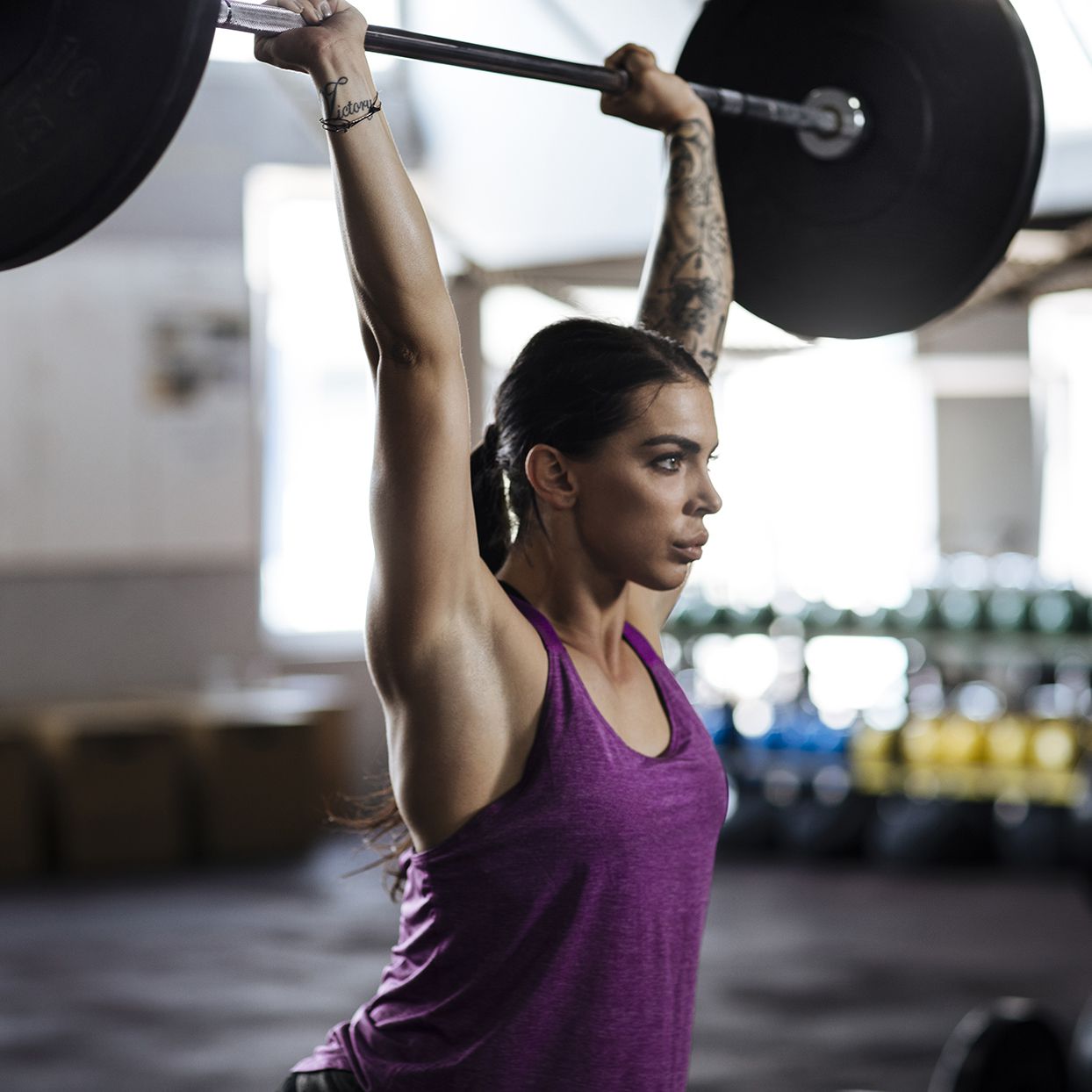 Young female in the gym lifting barbell