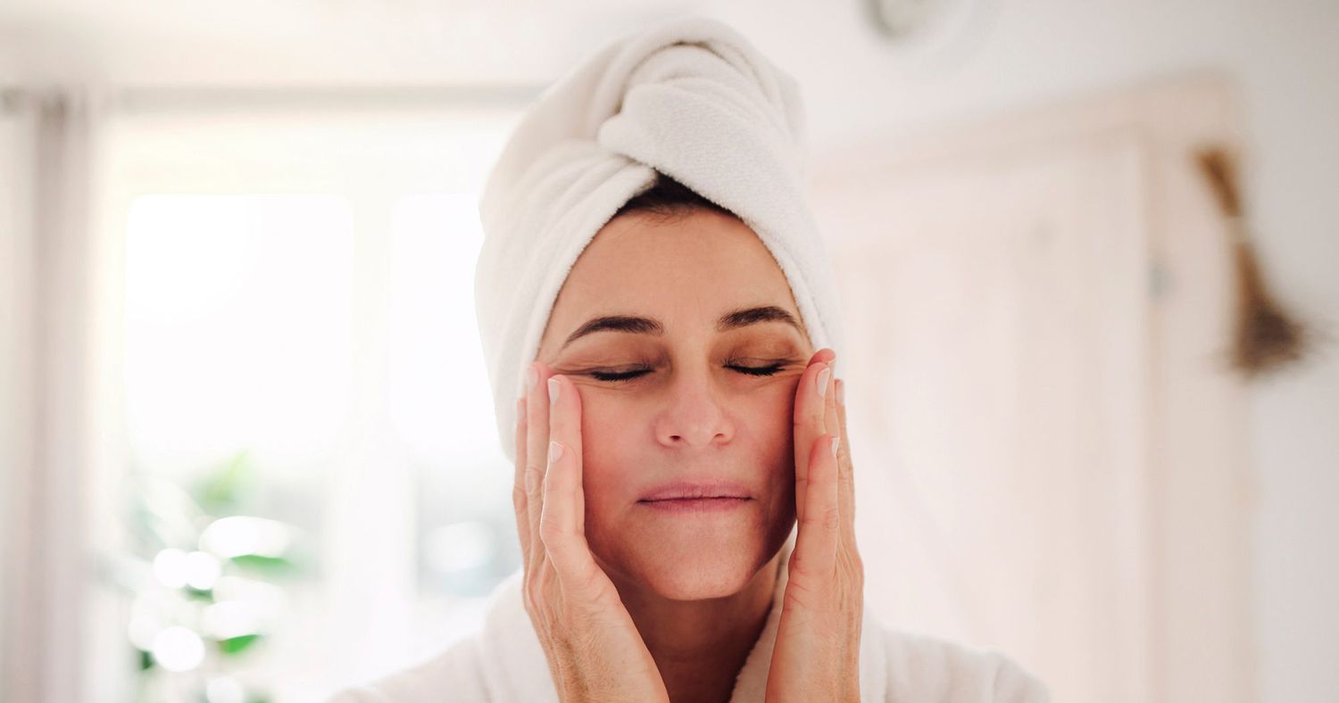 Portrait of Mature Woman in a Bathroom at Home Applying Moisturizer 2370x1244