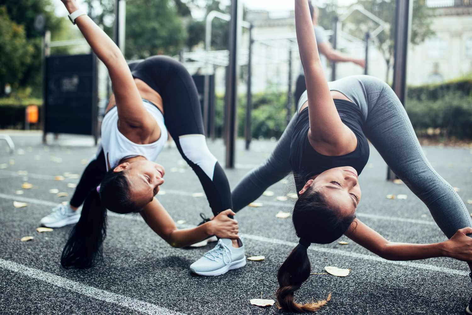 two women doing workout warm-up exercises at a playground