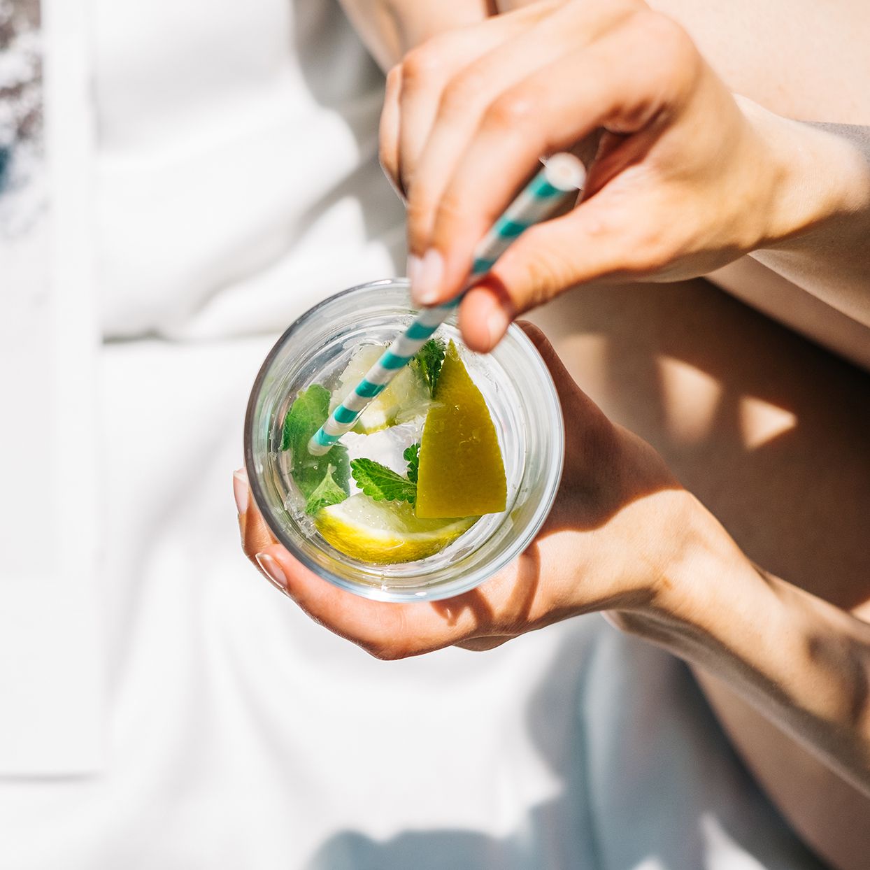 Woman drinking water with fresh lemon, lime and mint