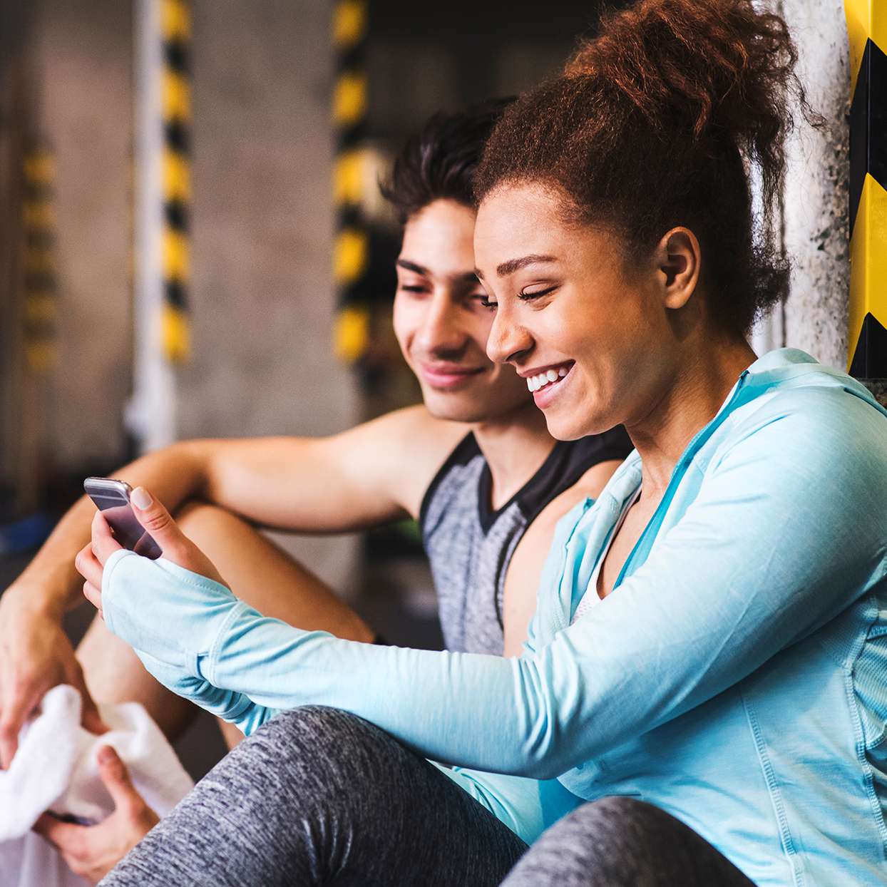 Two people looking at a fitness trainer on a phone