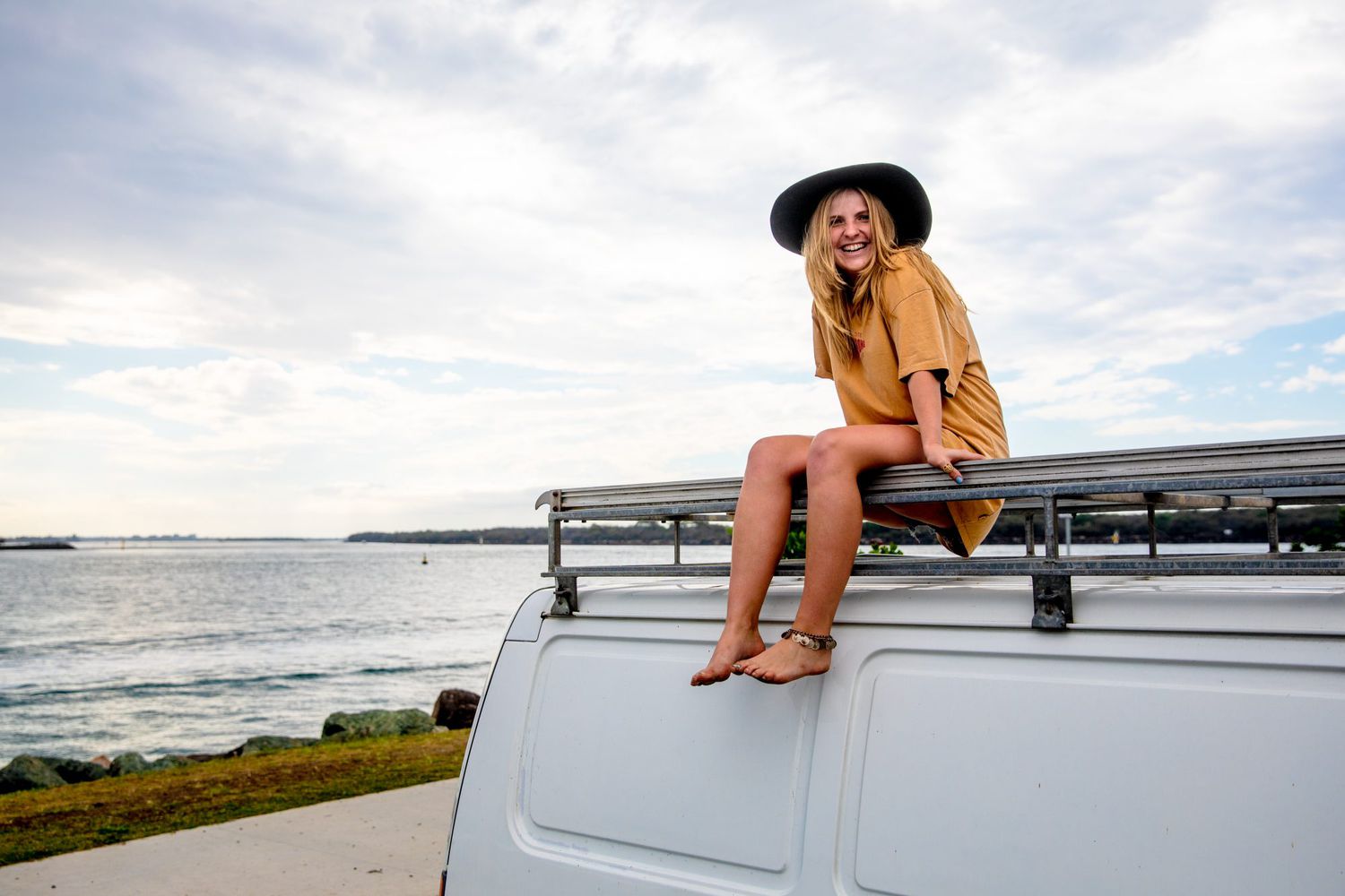 Woman travelling solo with her van and her surfboard by the Australian sea