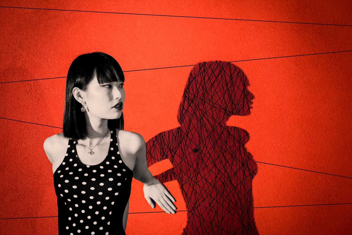 What Is Shadow Work? Young woman leaning against red wall, creating dramatic shadow with scribbles inside