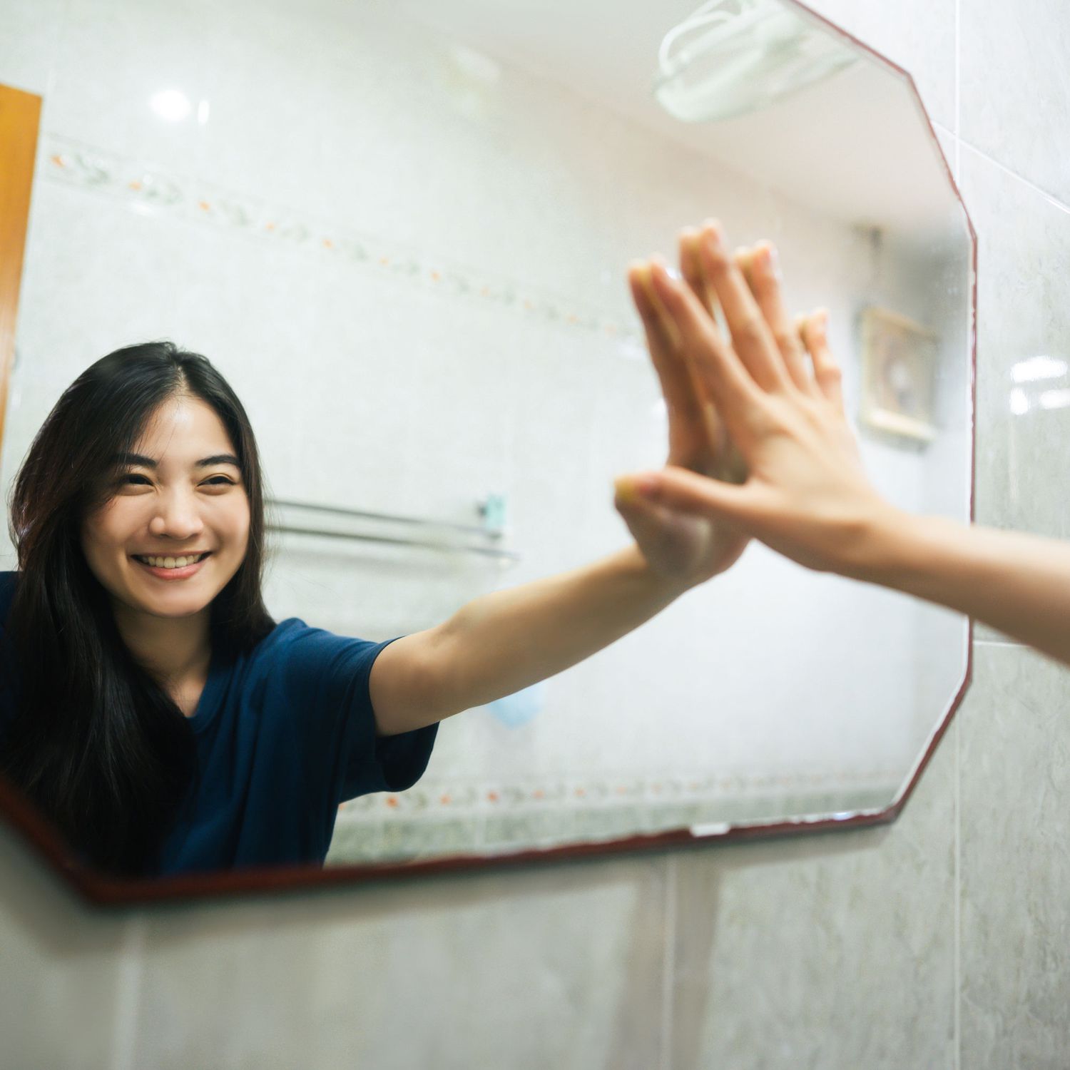 Woman_Holding_Hand_Up_To_Mirror
