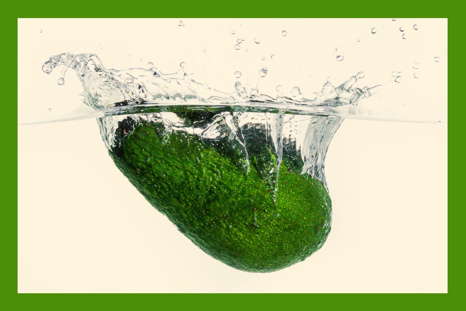 Ripe, green Avocado being dropped in water, creating a splash