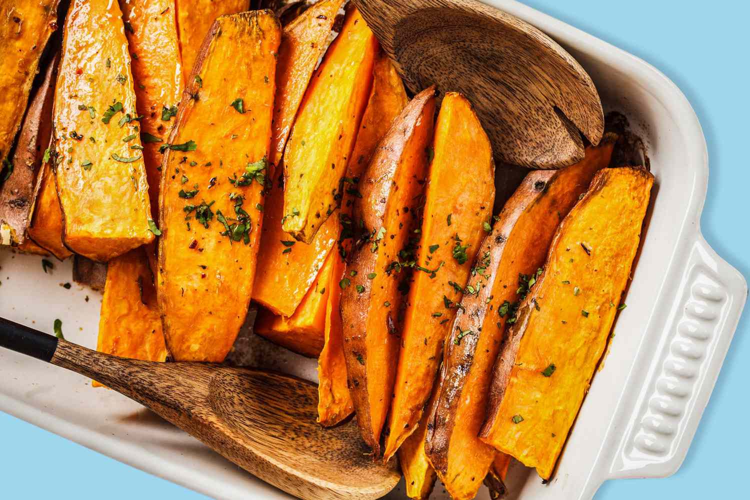 Roasted Sweet Potatoes on a white baking pan with herbs
