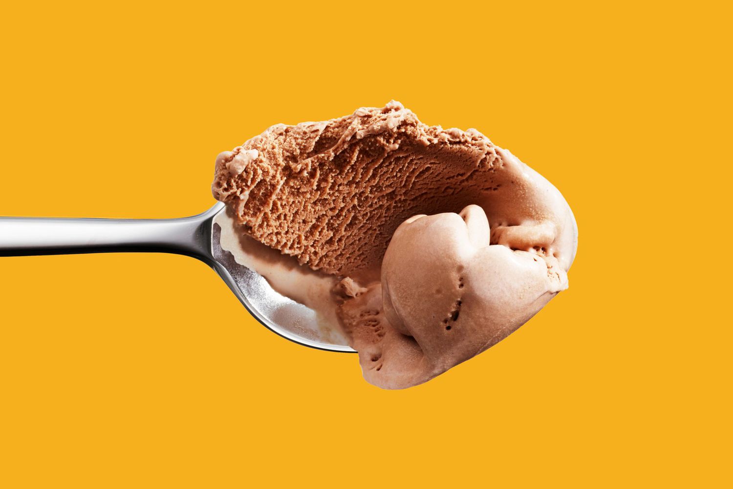 Spoon with a Scoop of chocolate ice cream against an orange background