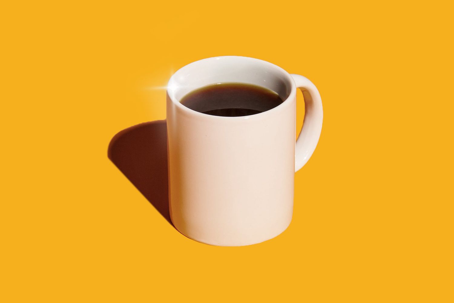 Cup of coffee sparkling in hard light against an orange background