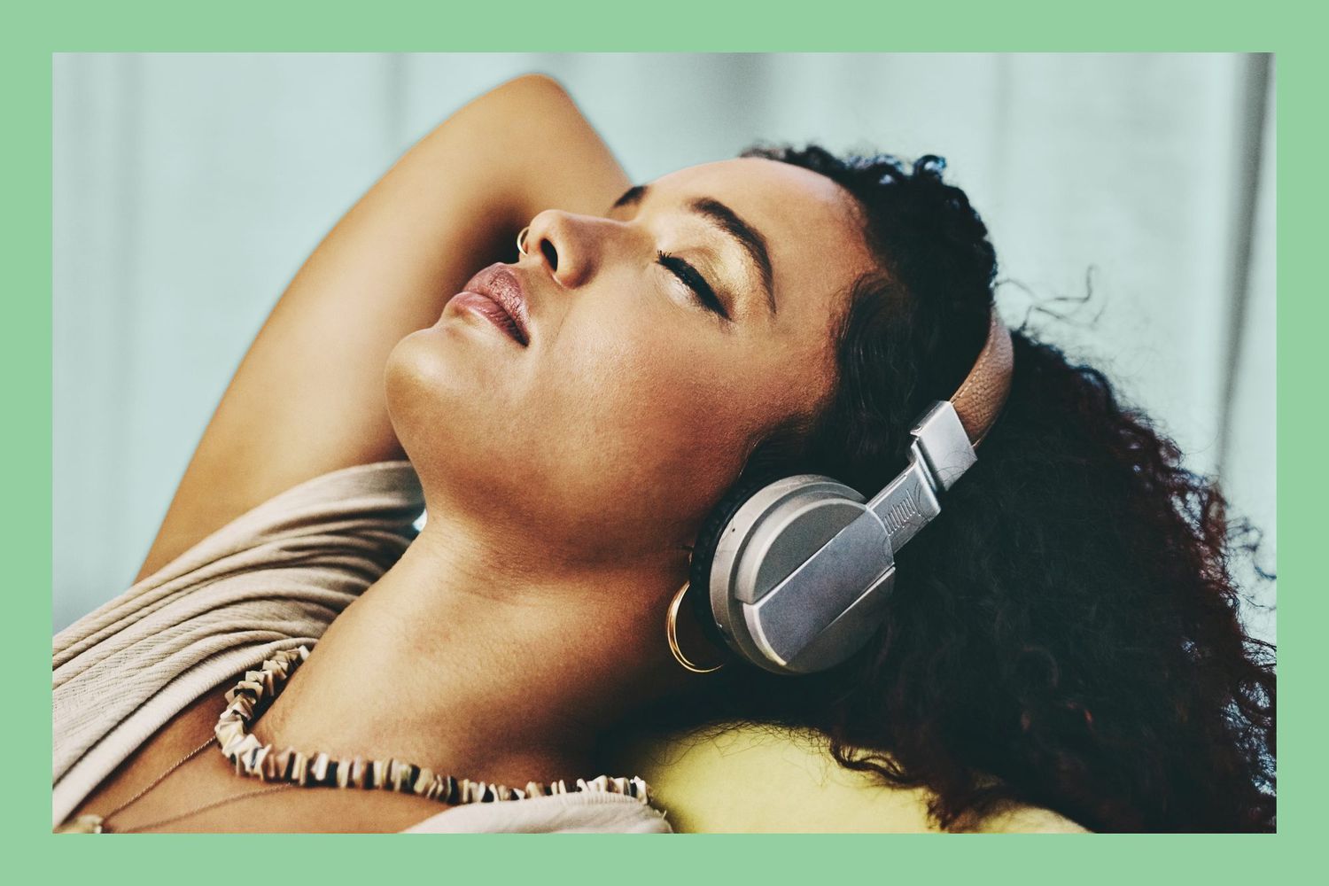 close up shot of a young woman wearing headphones while relaxing at home with eyes closed