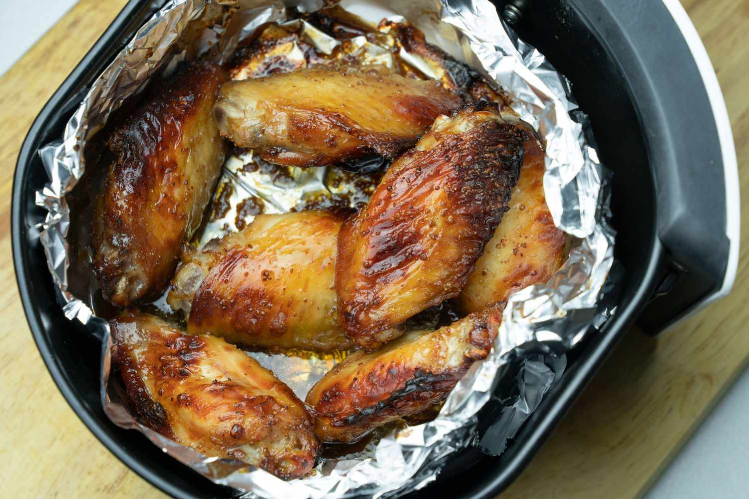 Air Fryer lined with aluminum foil and cooked chicken wings