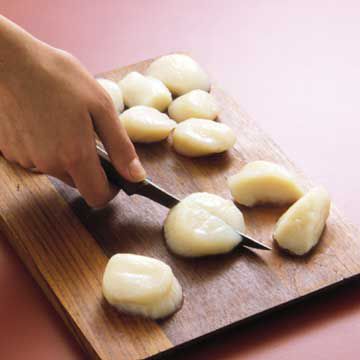 cutting scallops in equal sizes on cutting board