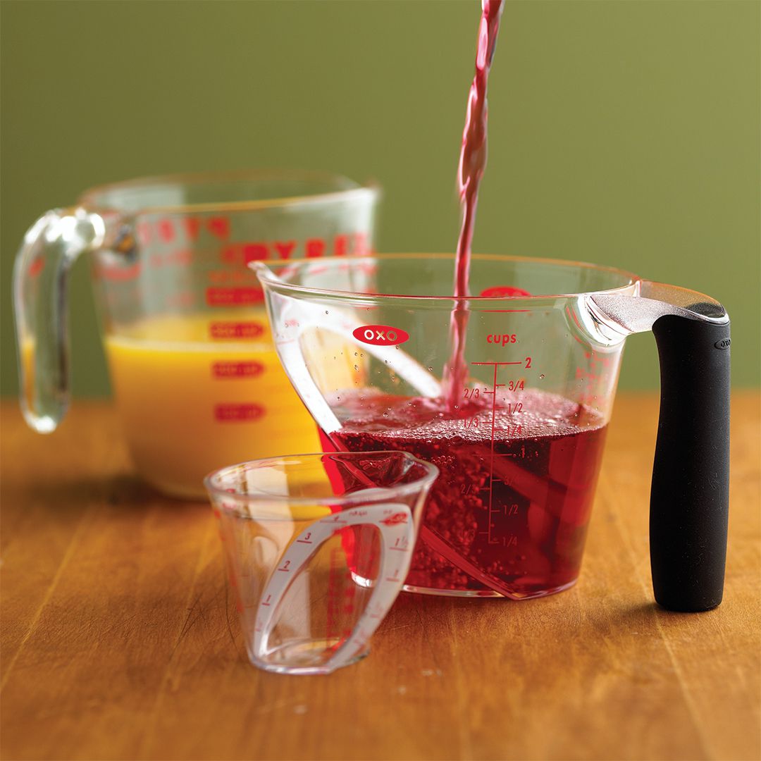 Measuring red liquid in liquid measuring cup juice wooden table