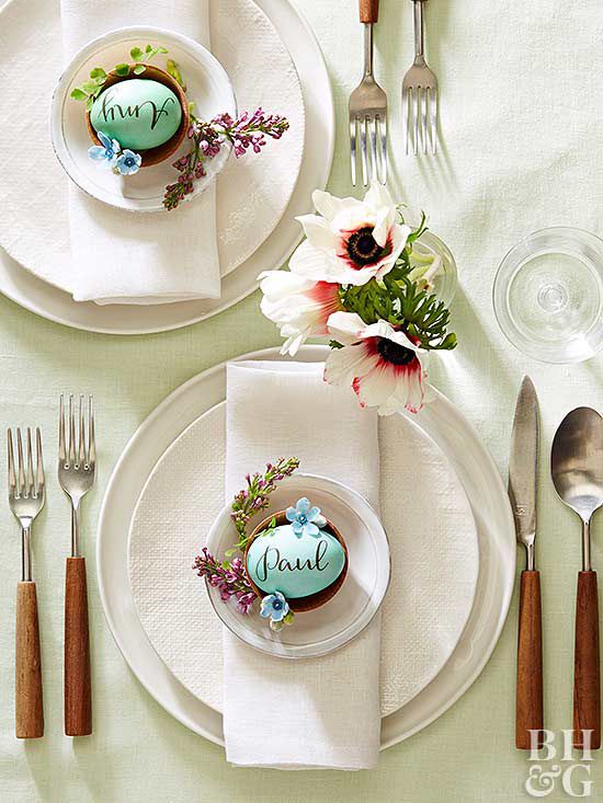 table setting with pretty spring flowers and blue easter eggs in center of plate