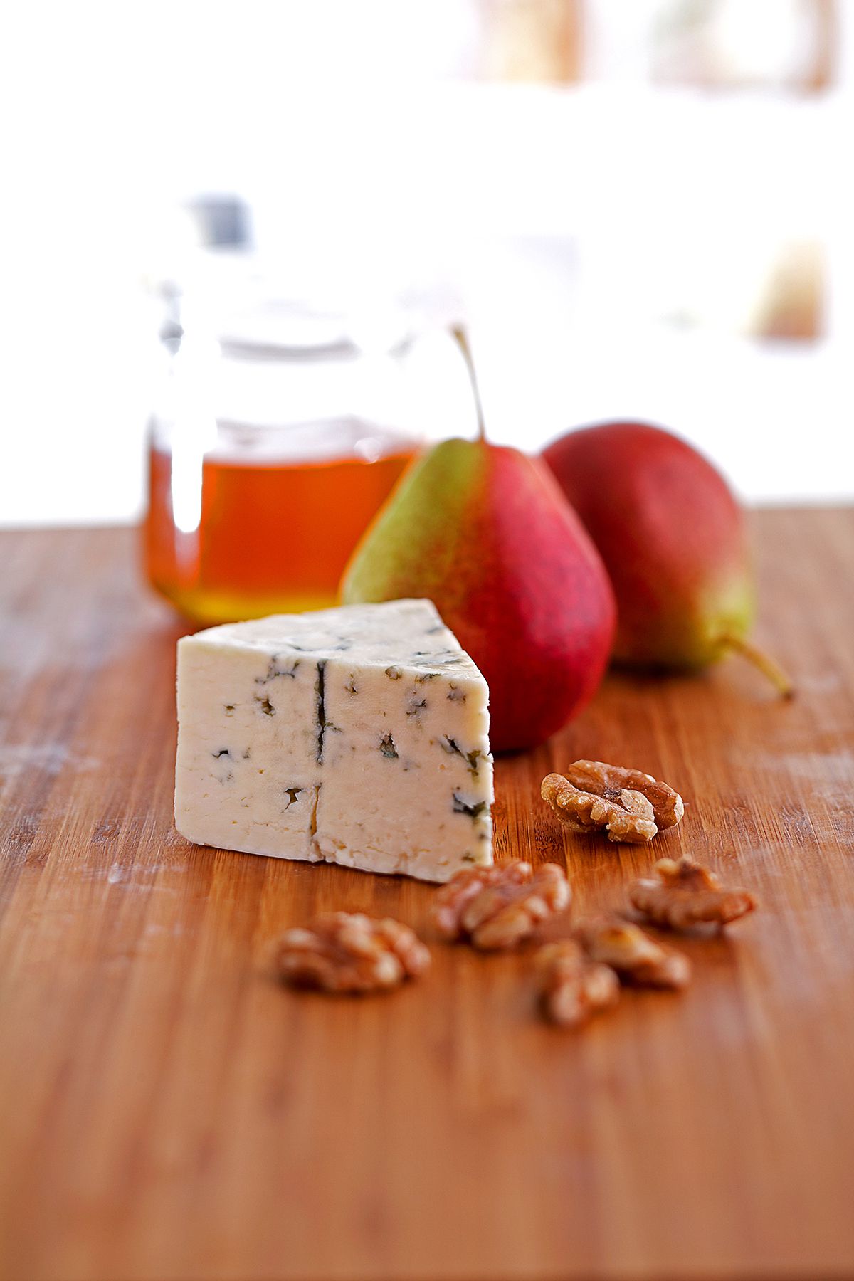 Wedge of blue cheese with a pear and pecans on wooden table