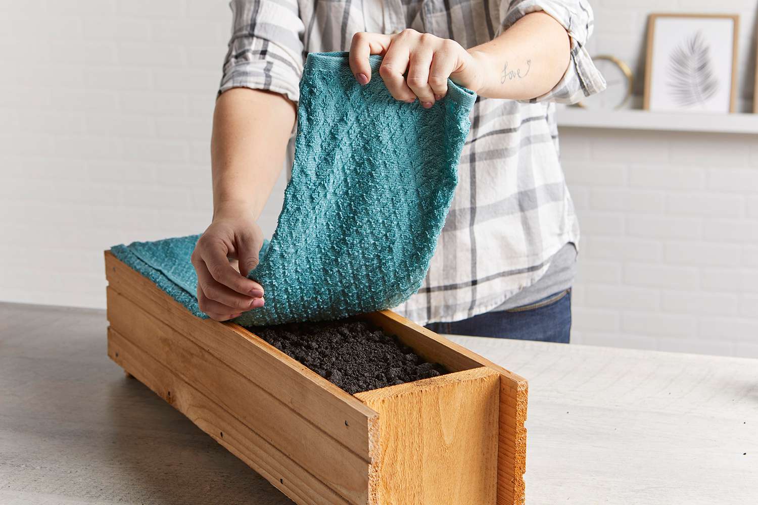 person placing blue towel on wooden planter