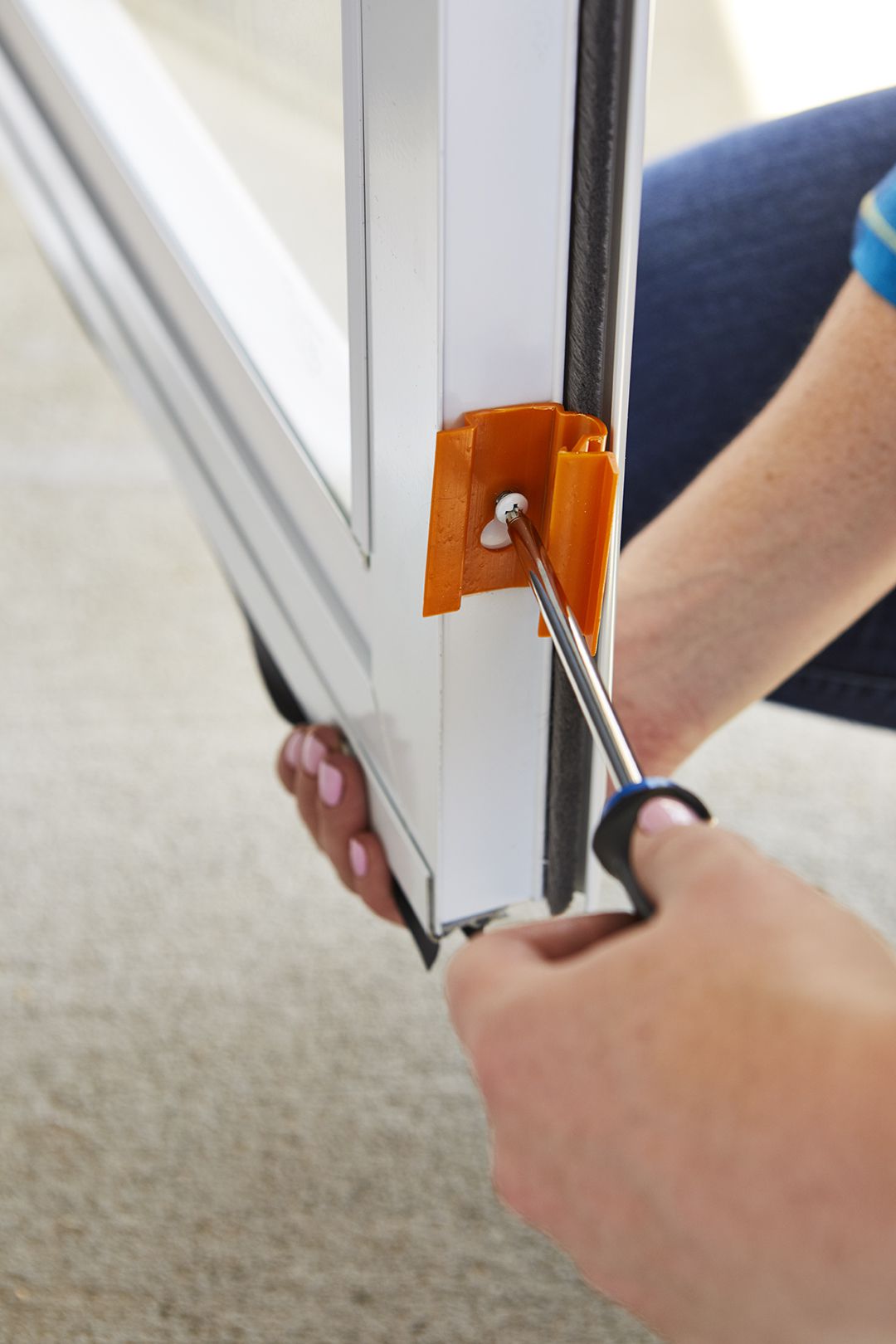 using screwdriver to tighten screw in storm door