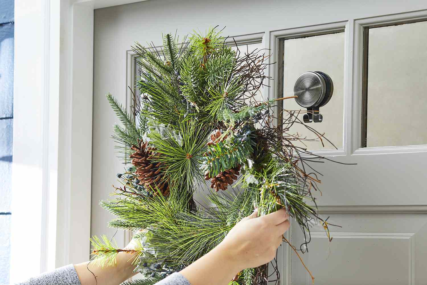 hook on glass holding evergreen wreath