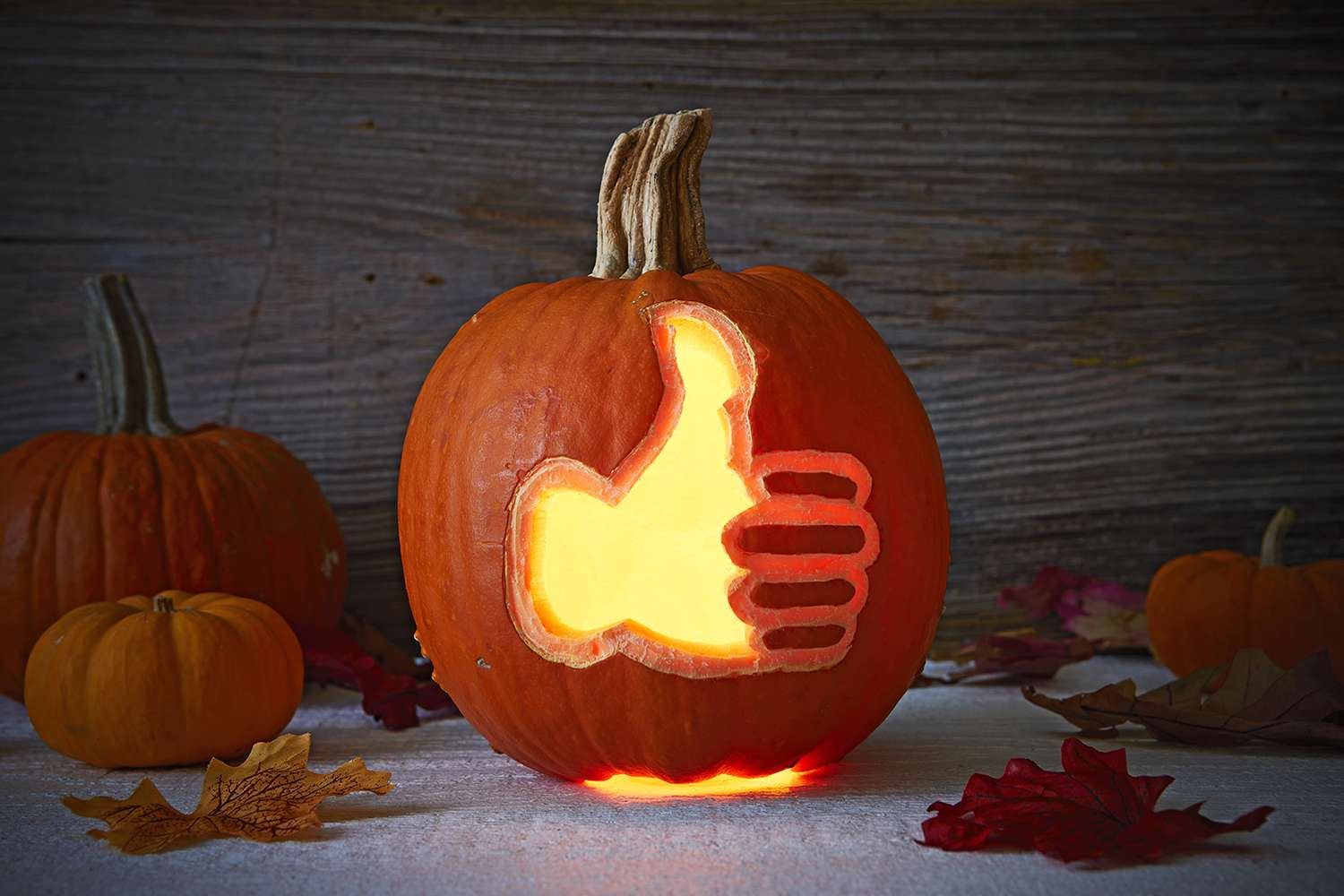 thumbs up symbol carved into lit-up pumpkin