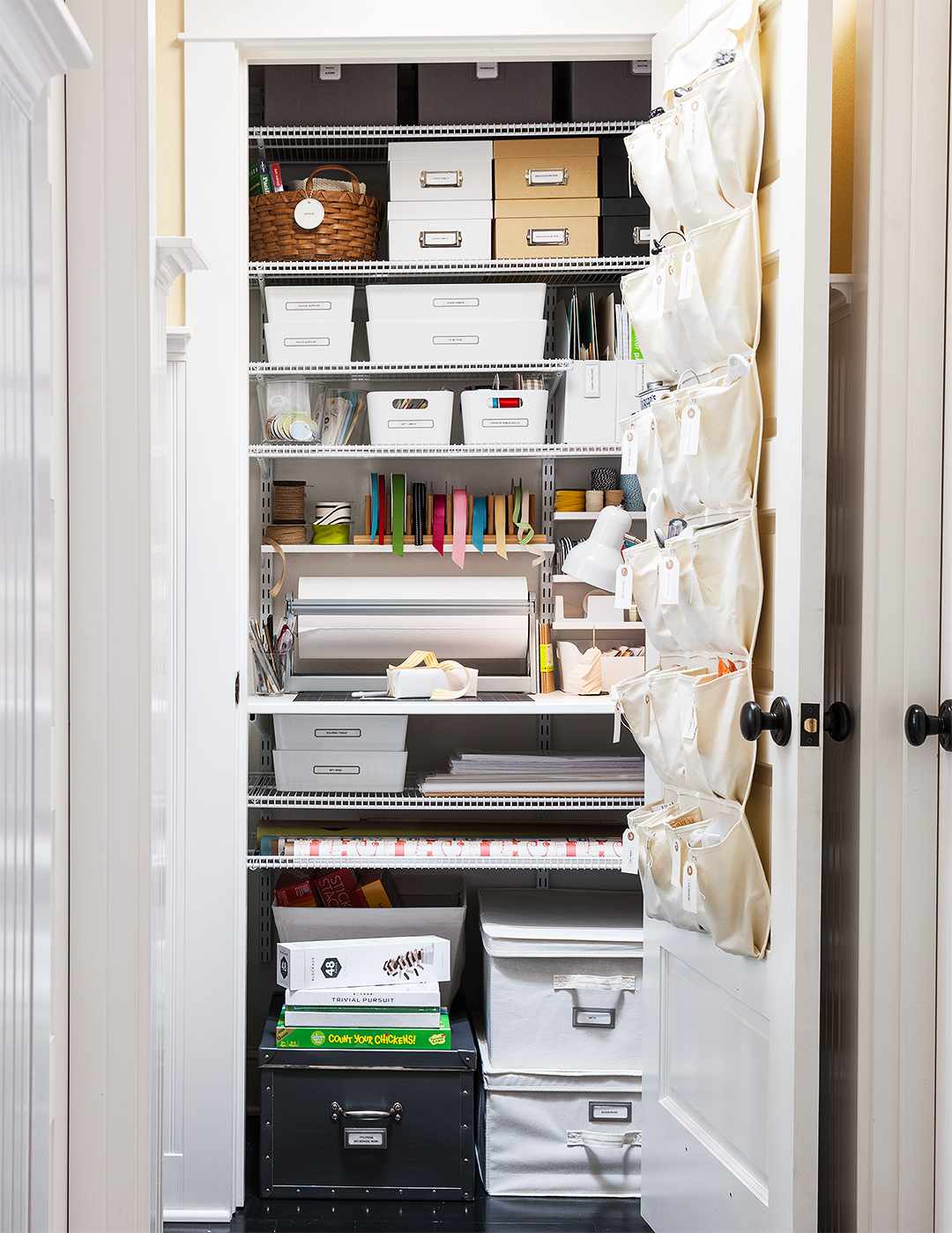 storage closet with various bins boxes and over the door shoe organizer