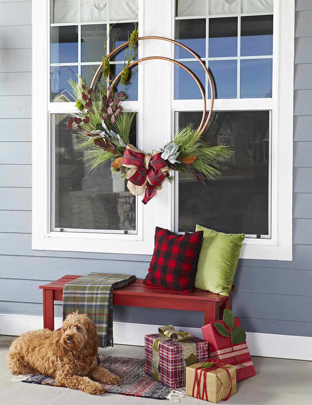 oversize Christmas wreath made of hula hoops hanging between windows outside