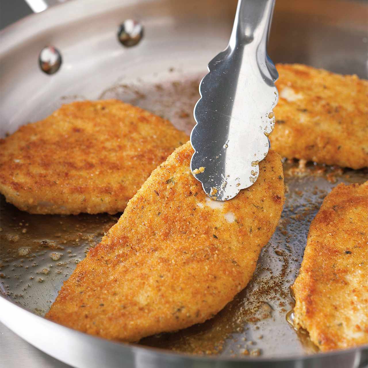 flipping breaded chicken with tongs