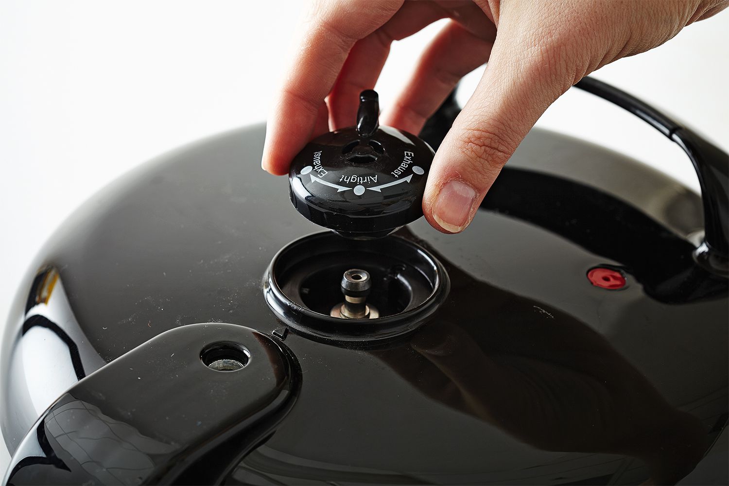 Pressure valve on black pressure cooker hand