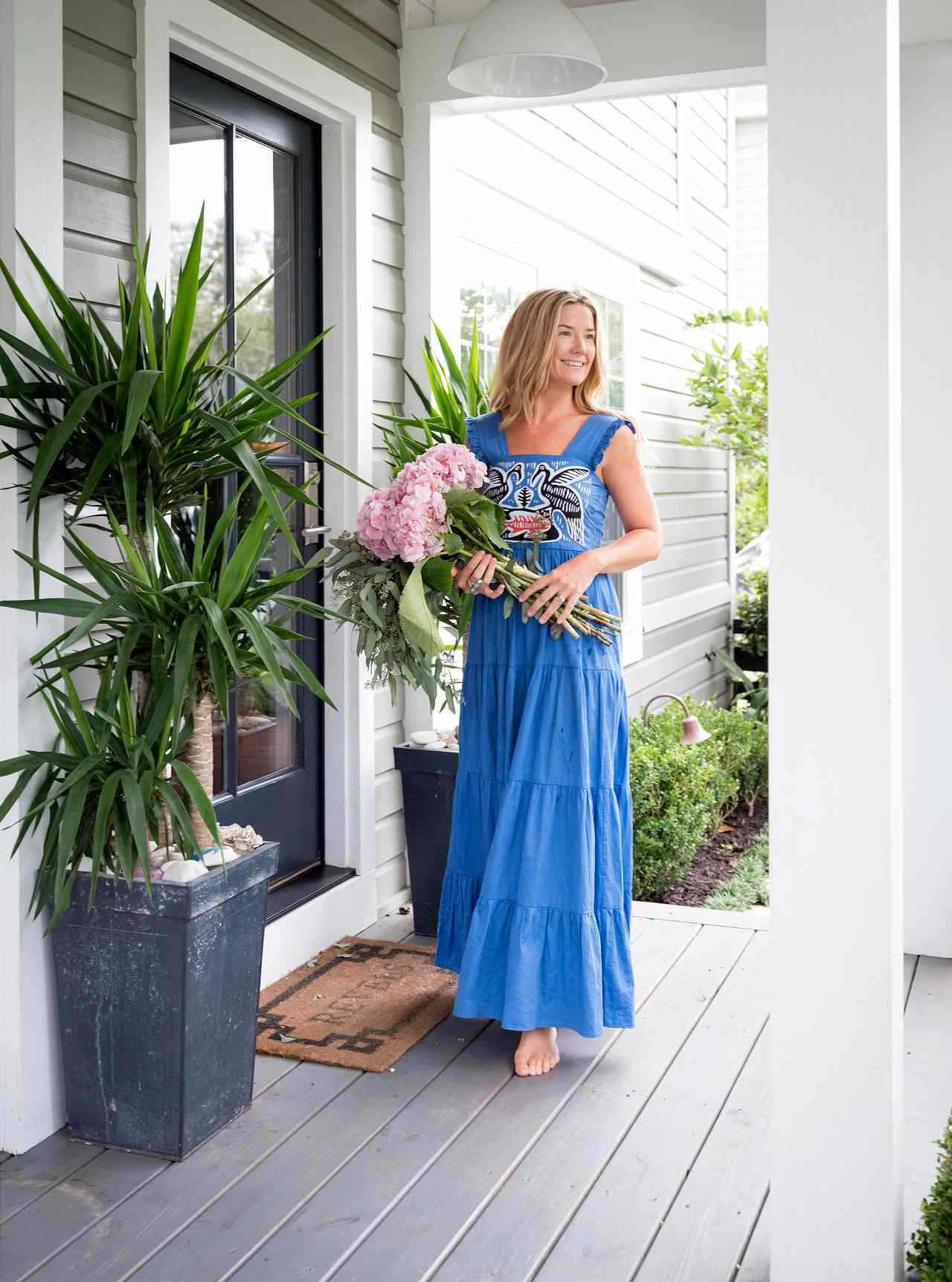 woman in blue dress holding flowers near door
