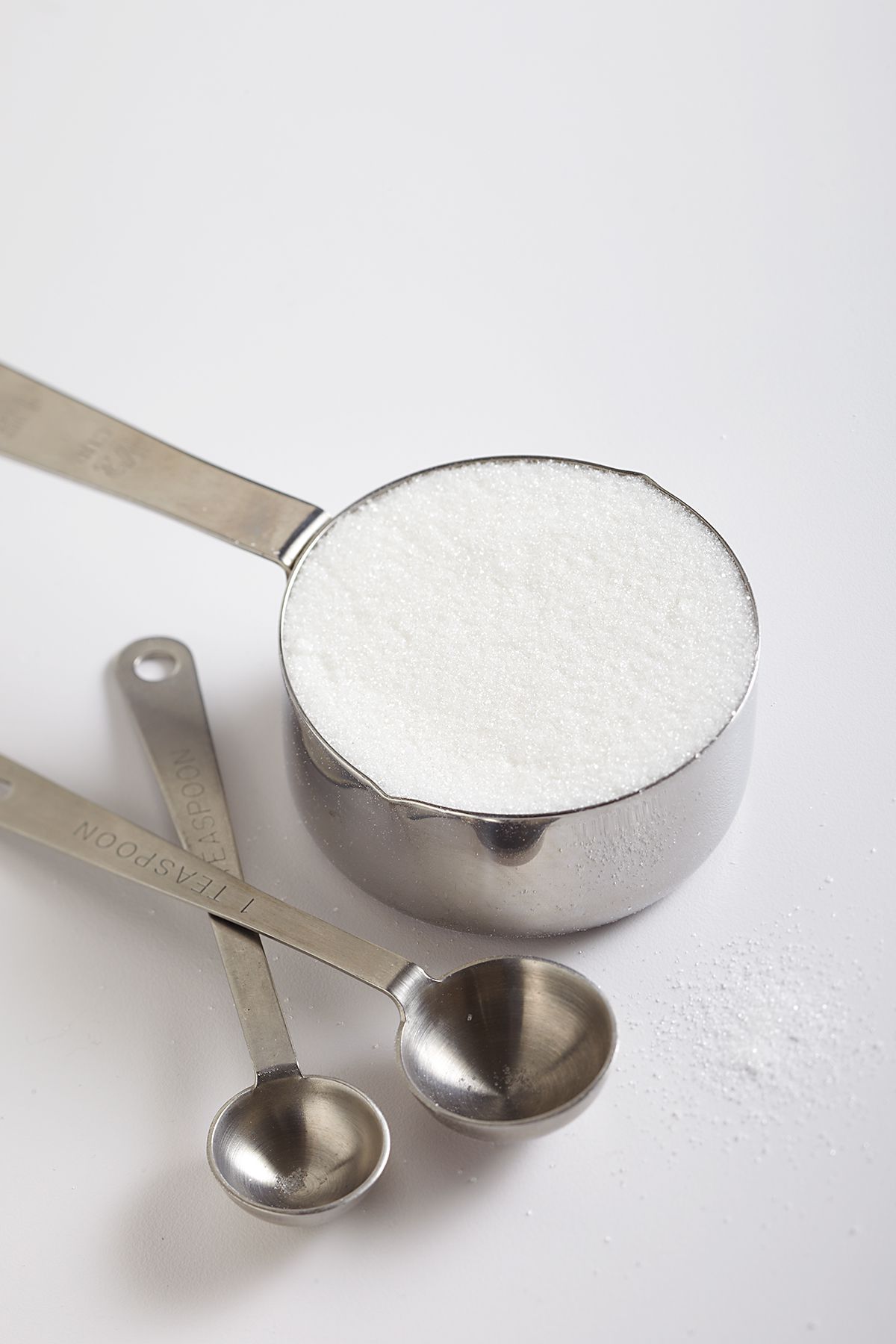 Sugar in silver measuring cup with measuring spoons