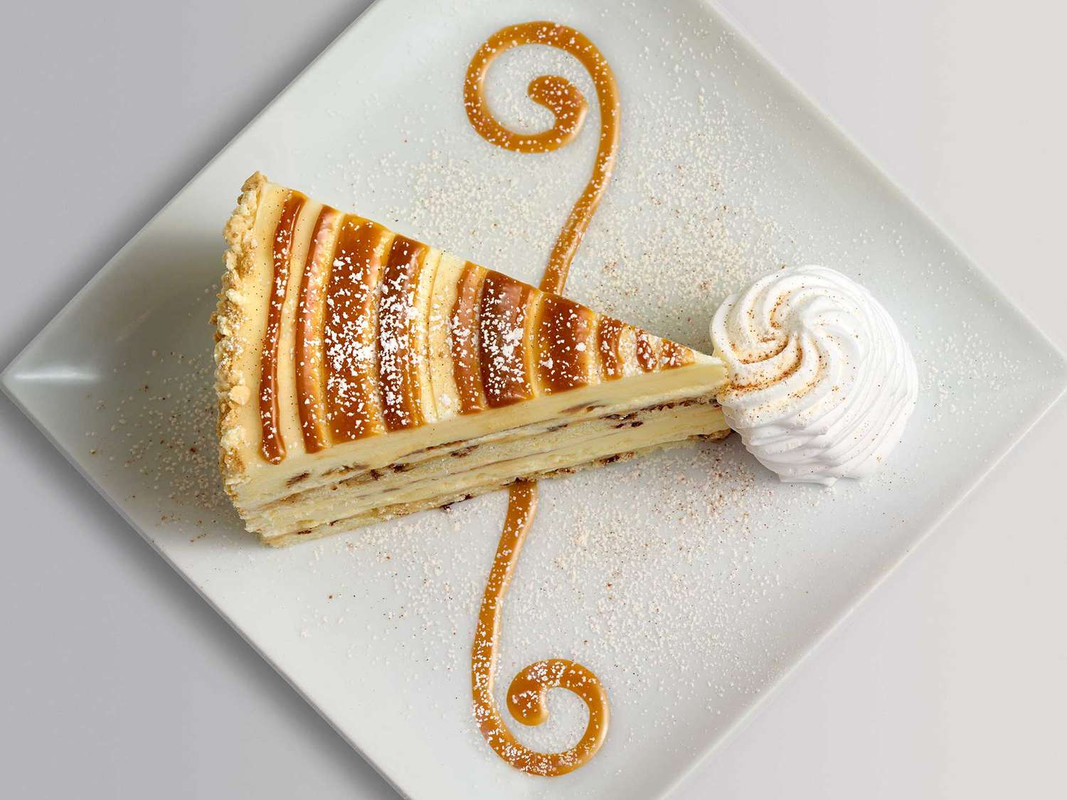 Slice of Cheesecake Factory Cinnabon Cinnamon Swirl Cheesecake on a plate with whipped cream