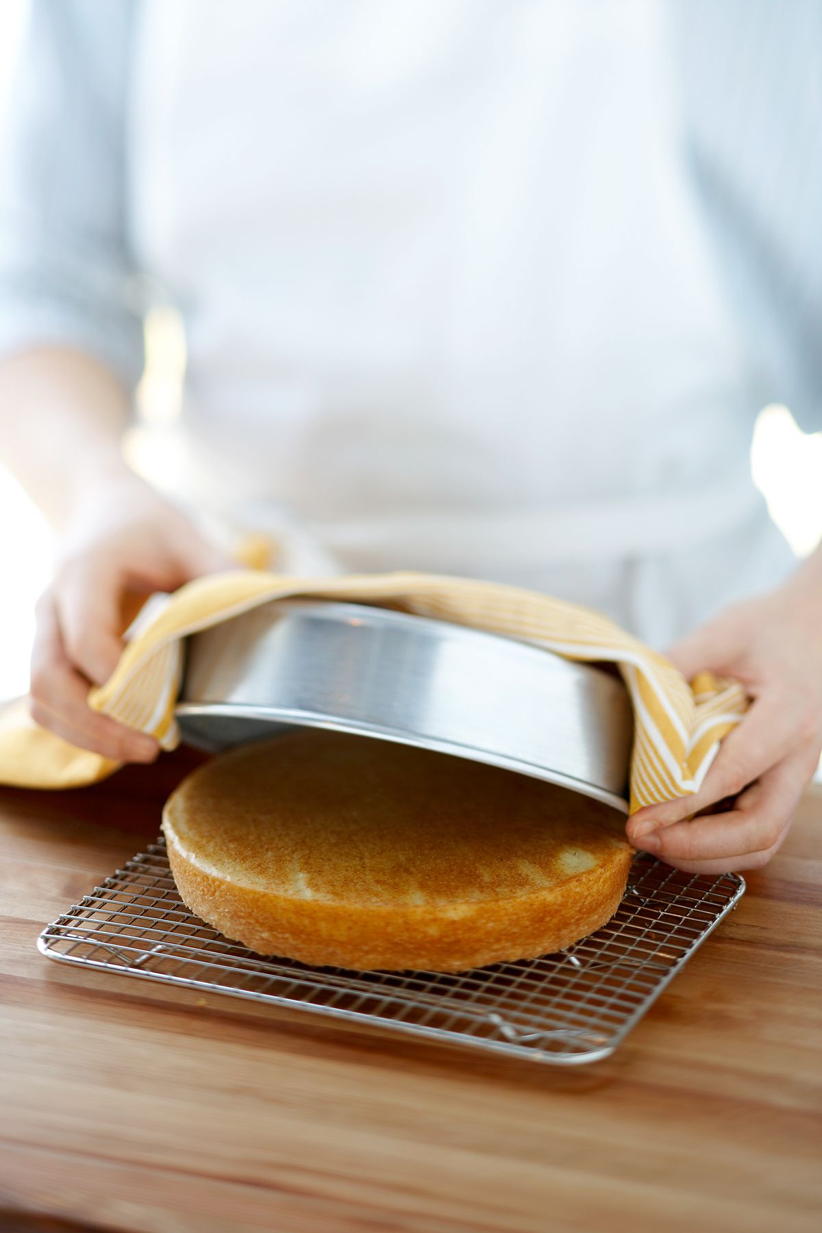 baker placing cake from cake pan on wire rack