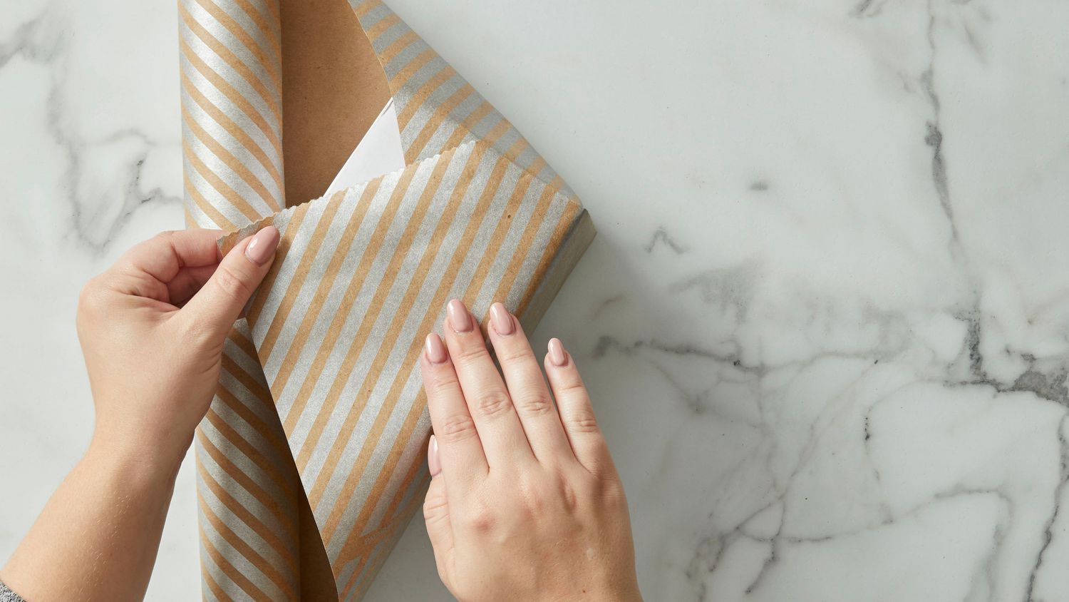 Folding brown striped gift wrap paper over a gift