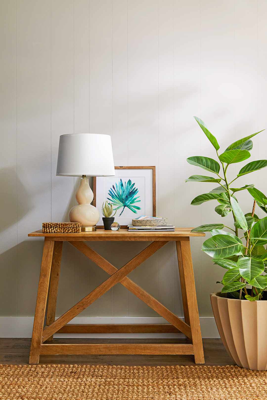 table and plant in front of painted wood paneling wall