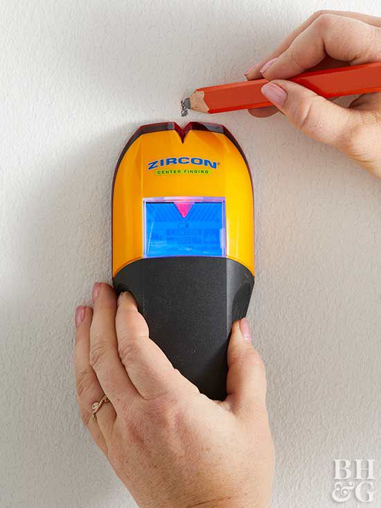 using stud finder and marking wall with pencil