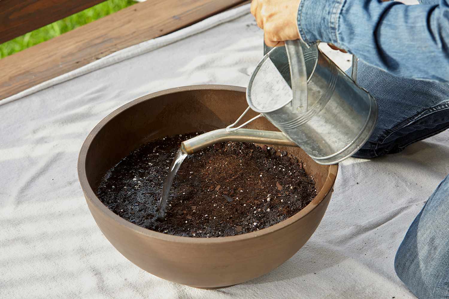 watering soil inside planter bowl