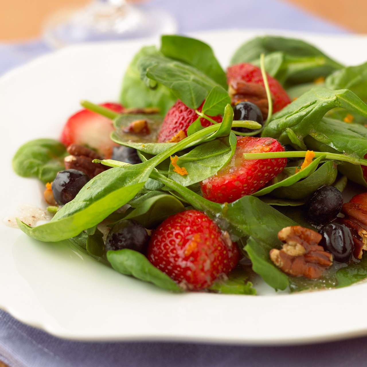 Spinach-Berry Salad with nuts on white plate