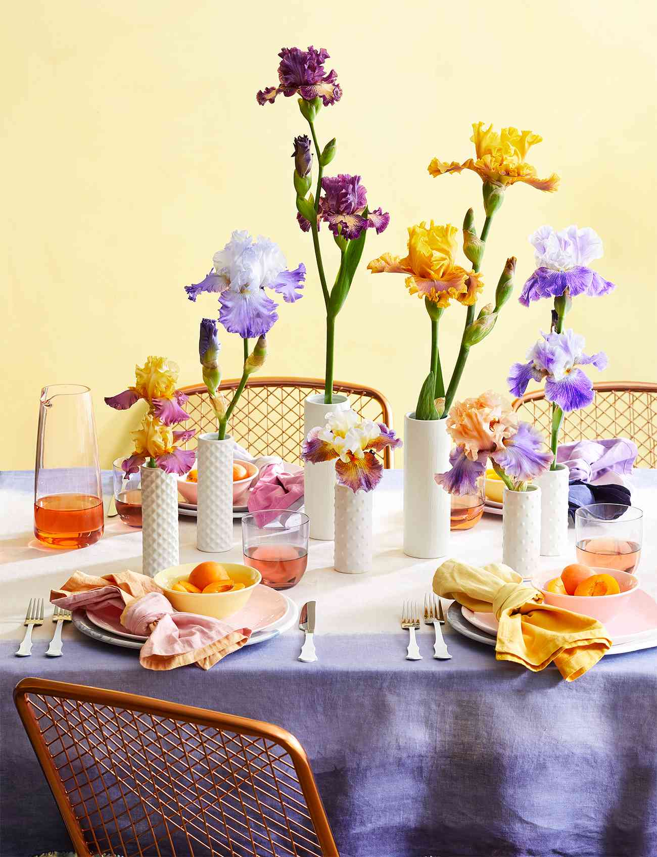 table setting with flowers in white vases yellow background