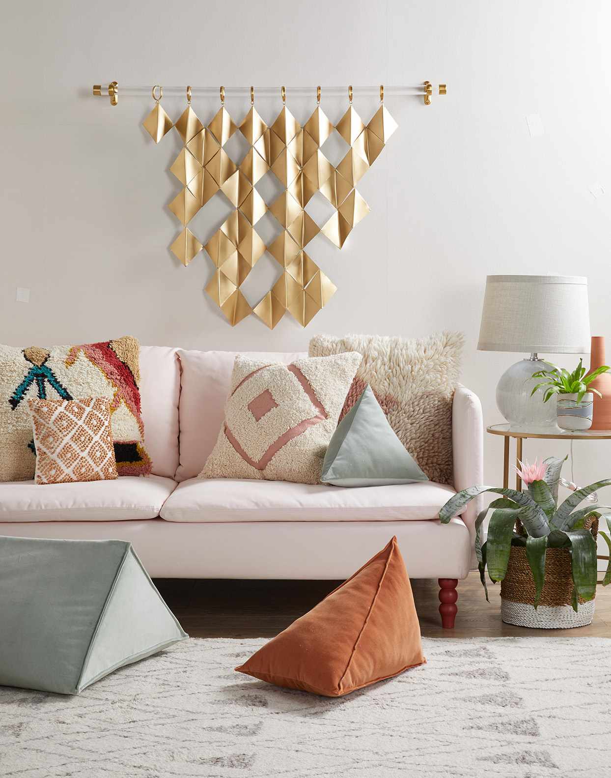 Gold wall hanging above pink sofa in living room