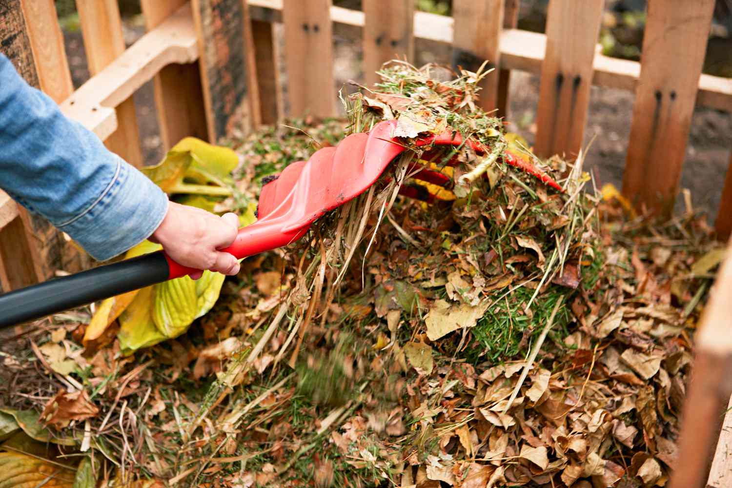 using red pitchfork to build compost pile