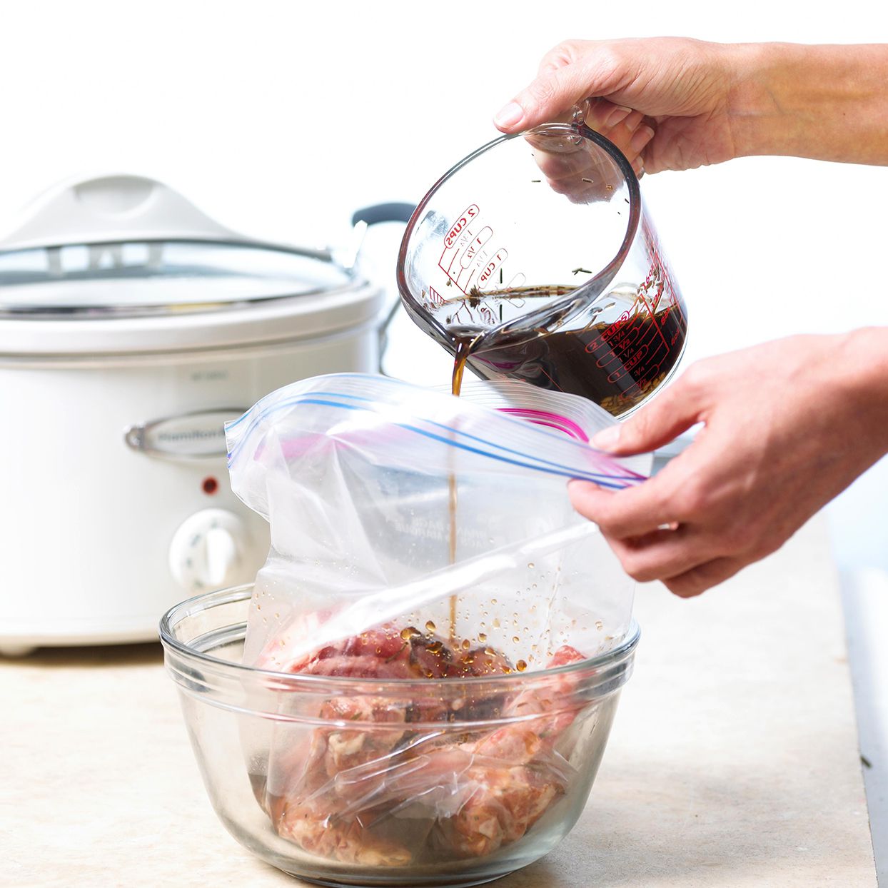 pouring marinade into plastic bag with meat