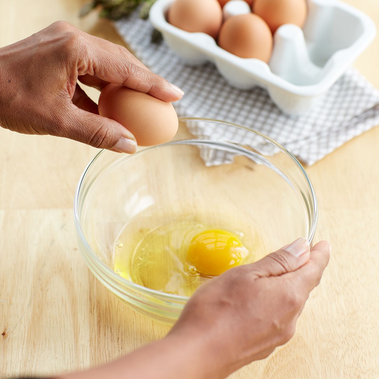 Hand cracking an egg on the side of the bowl