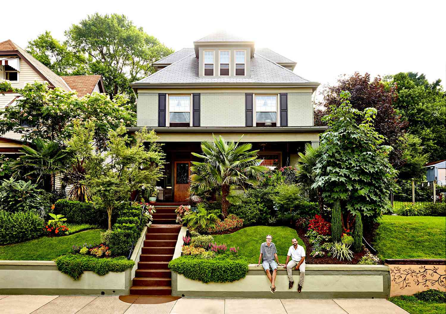 Front yard with multiple plants with two people sitting