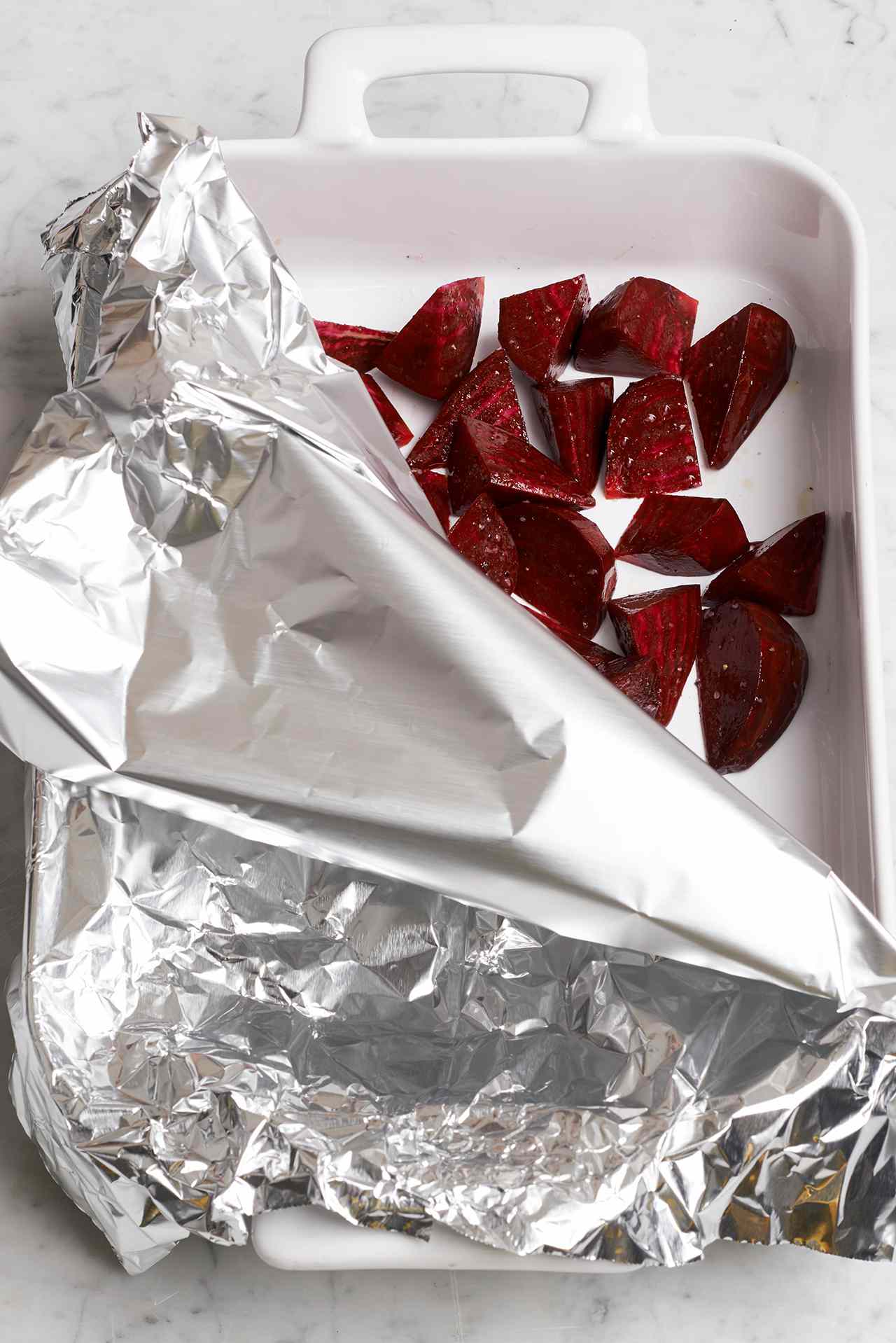 chopped beets in white baking dish with foil