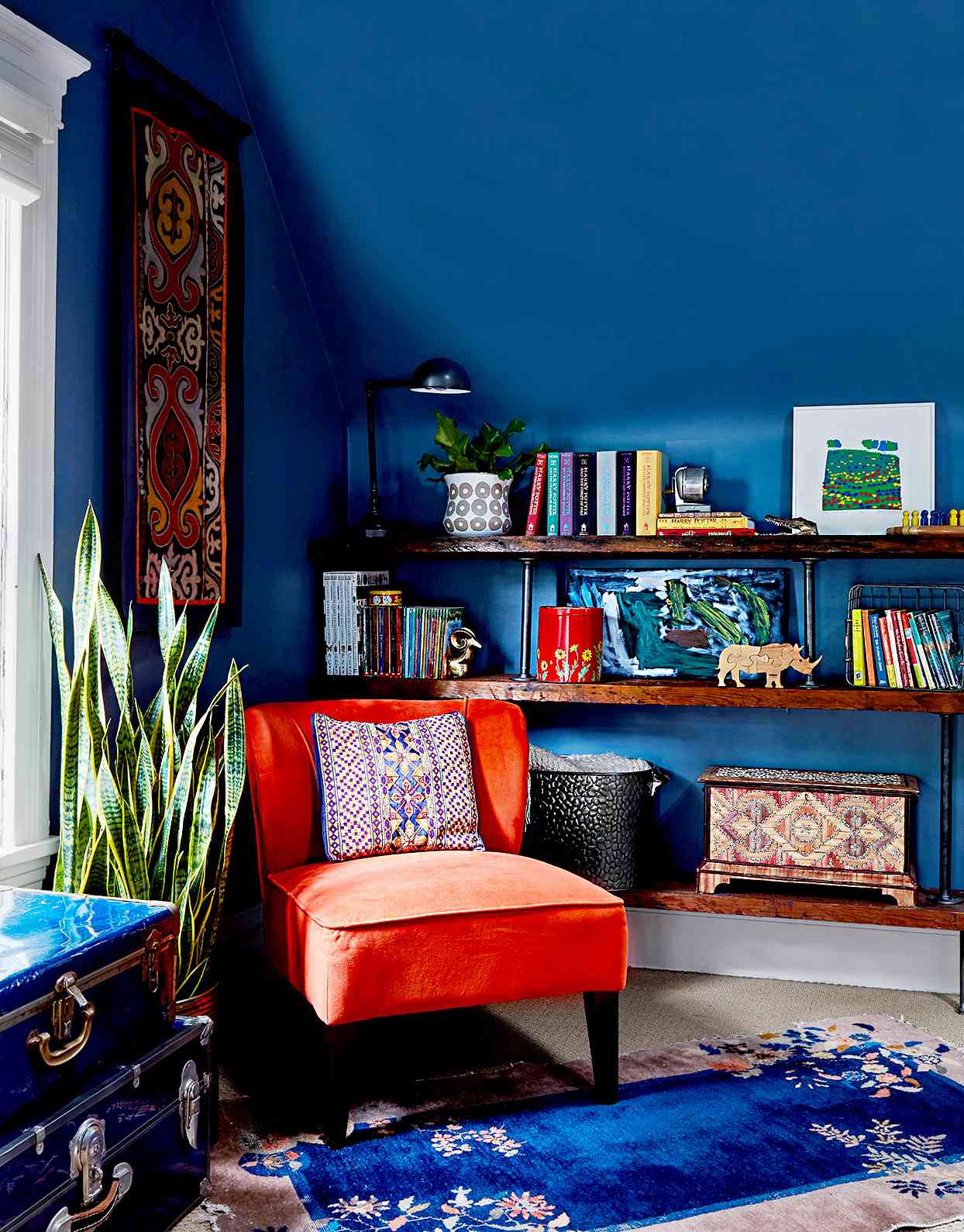 Dark blue walls with orange chair and shelving