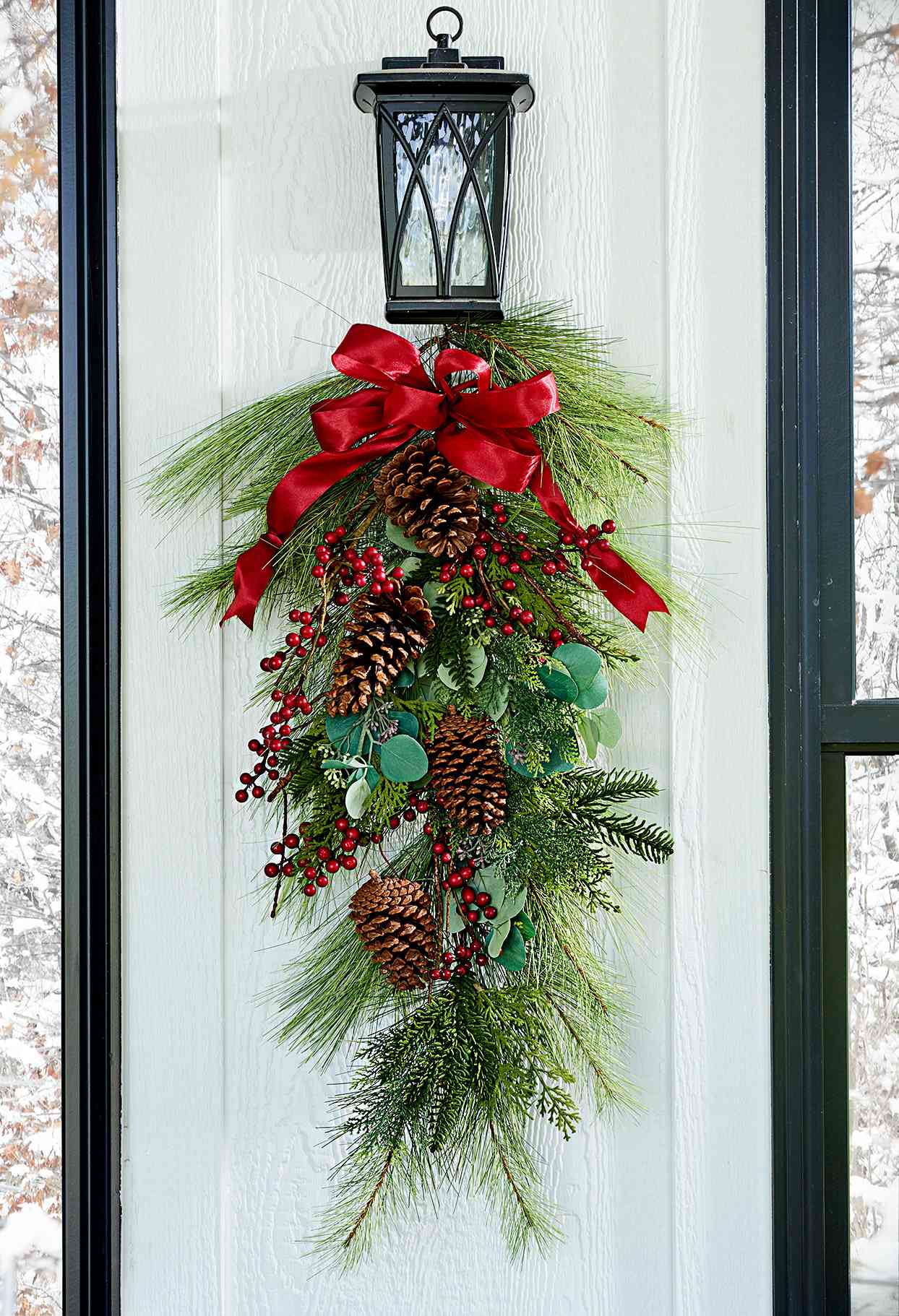 Door wreath made of evergreen, holly, and pinecones