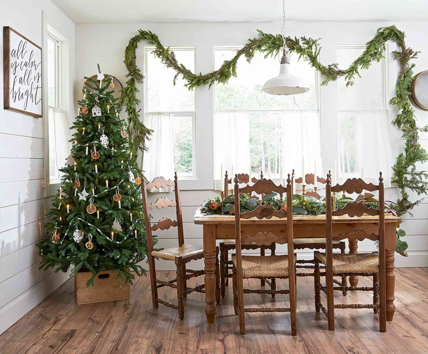 farm dining table near Christmas tree in crate and garland above window