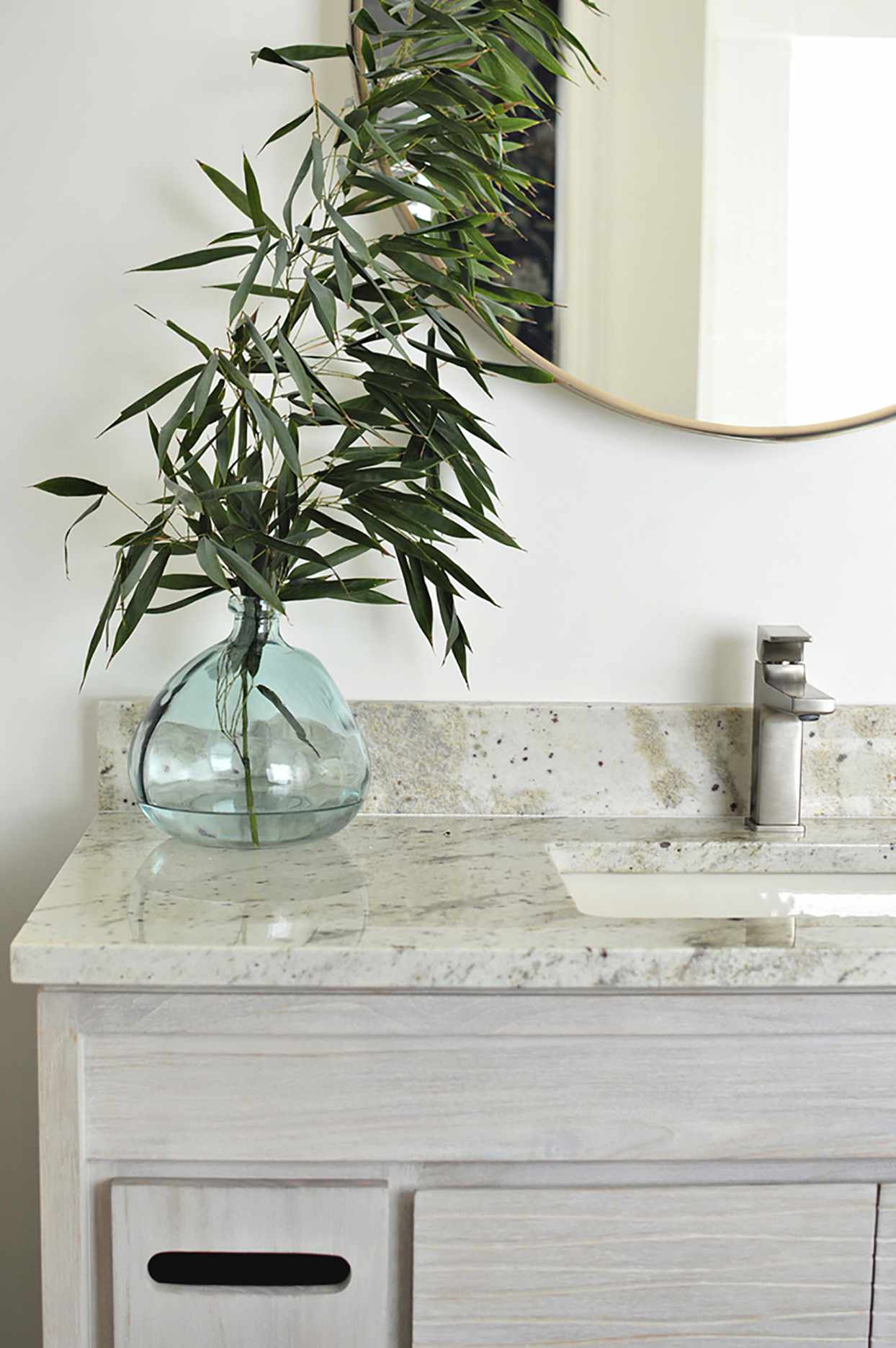 bathroom counter and sink area with glass vase and plant