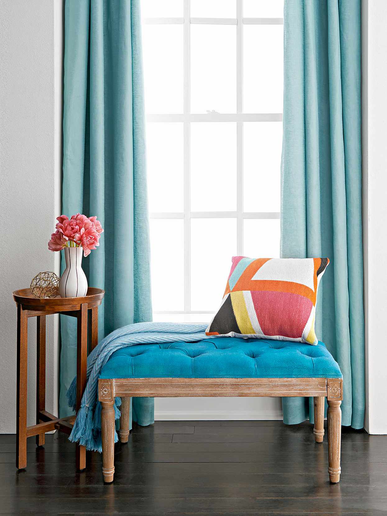 blue bench in front of window with throw and geometric curtains