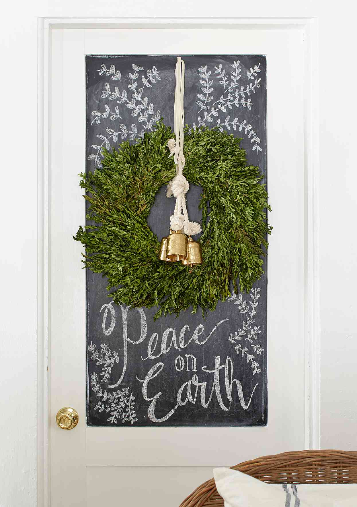 chalkboard-painted door inset with writing, hanging wreath and bells