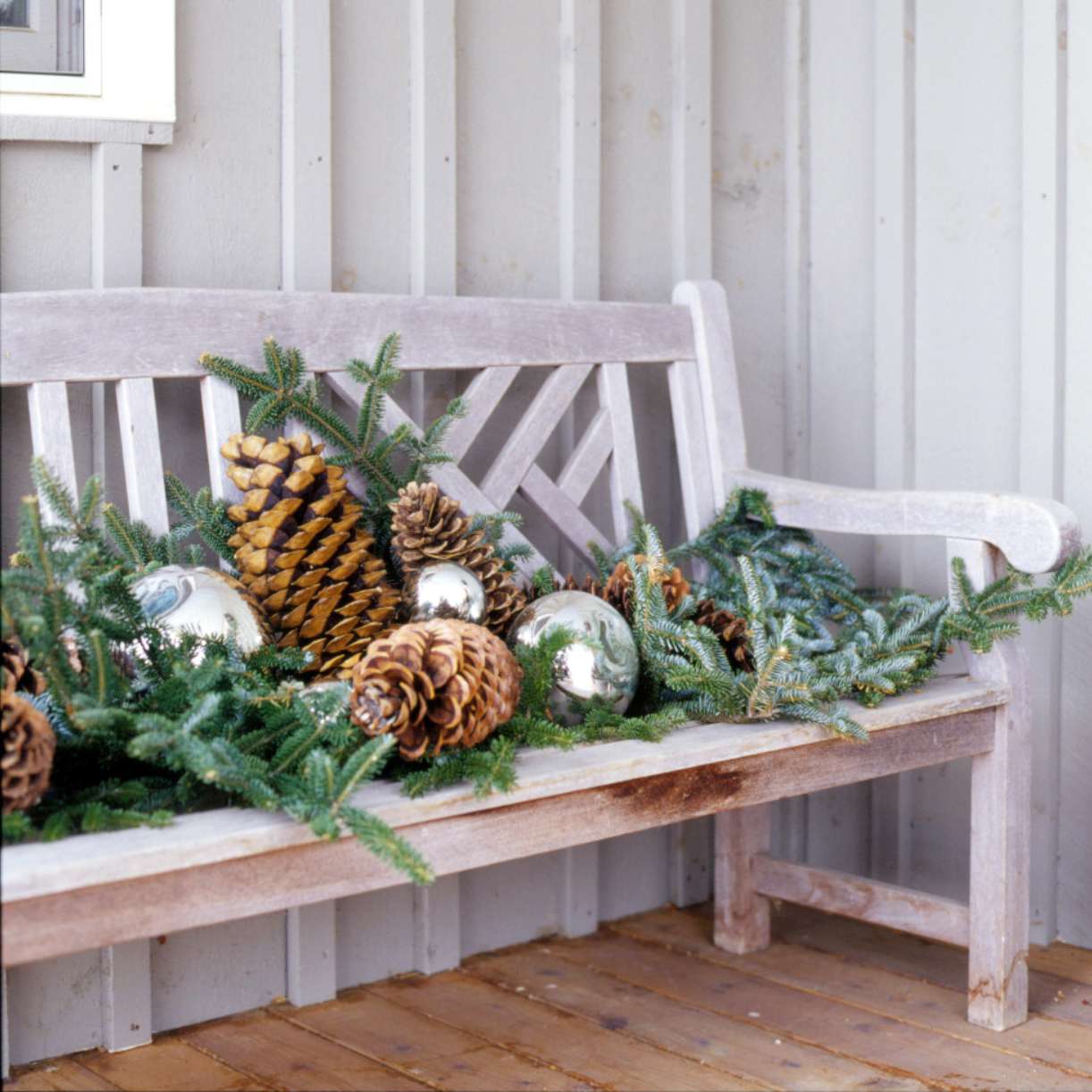 bench decorated with greenery pinecones and orbs
