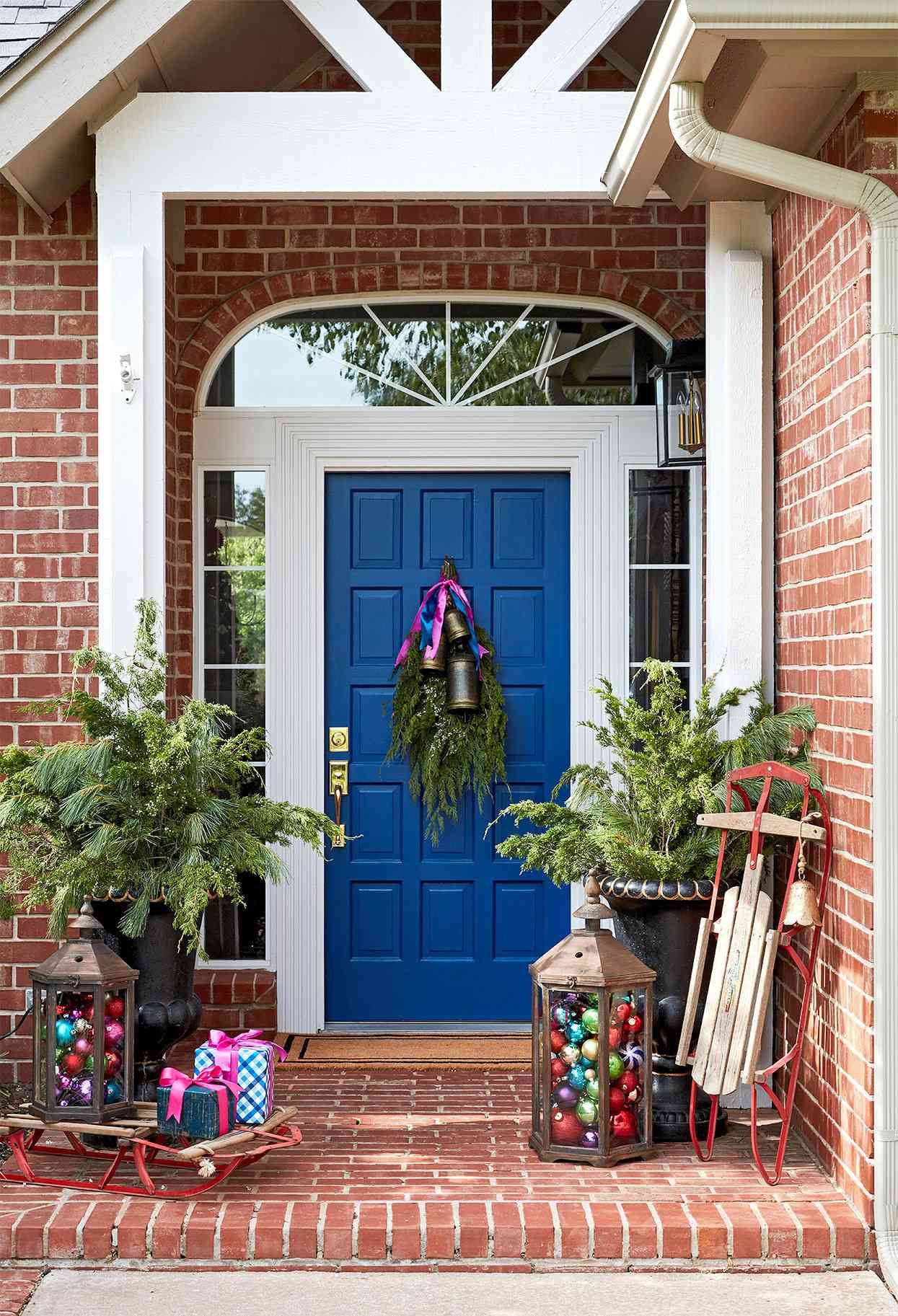vintage sled, ornaments and gifts displayed on brick front porch